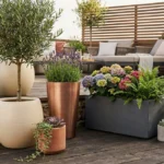 Terrasse aménagée avec une variété de pots design (céramique, cuivre, anthracite) et diverses plantes : olivier, lavande, hortensias.
