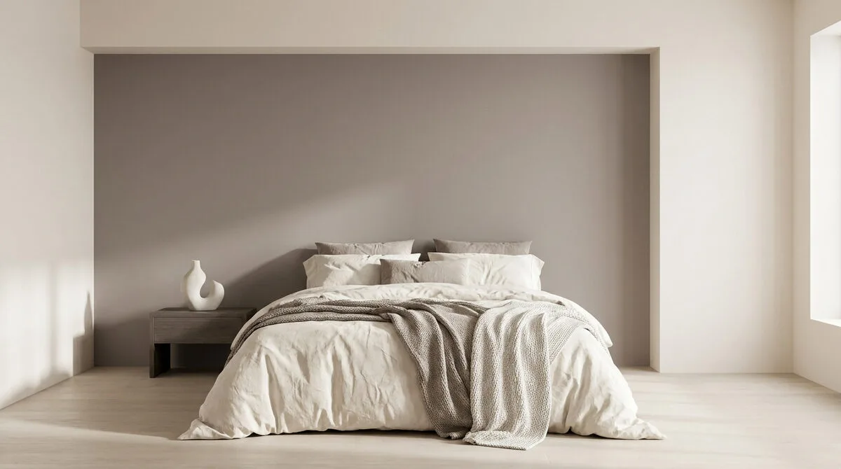 Lit double au centre d'une chambre minimaliste avec un mur d'accent taupe et une décoration épurée.
