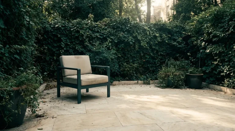 Fauteuil d'extérieur seul sur une terrasse pavée entourée de végétation sauvage